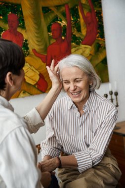 Sanat stüdyosunda iki kadın sanat eserinin önünde oturur..