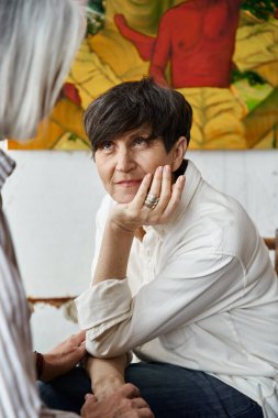 Sanat stüdyosunda resim yapmayı tartışan iki kadın.