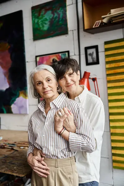 stock image A mature lesbian couple standing together in an art studio.