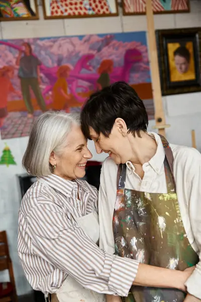 stock image A mature lesbian couple standing in an art studio together.