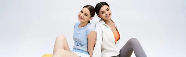 stock image Two pretty, brunette teenage girls in sportive attire sitting closely together, showcasing friendship and camaraderie.