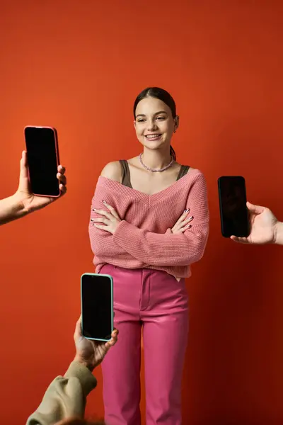 Brunette Woman Stands Red Wall Cell Phones Symbolizing Communication Technology — Stock Photo, Image