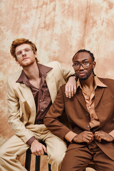 Two multicultural men with elegant style sitting together.