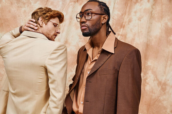 Two diverse men stand side by side, exuding elegance in their dapper style.