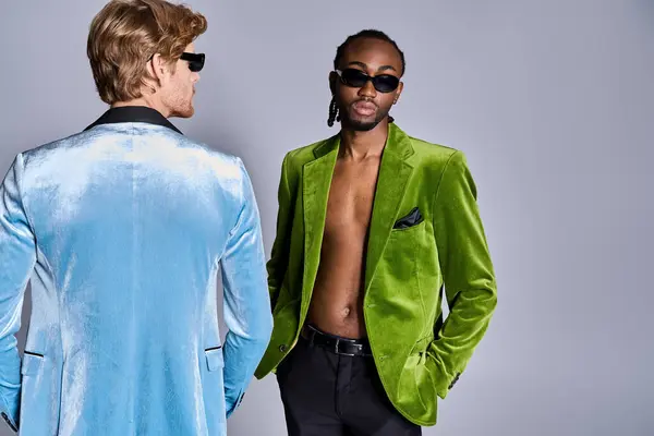 stock image Two handsome multicultural men in green jackets pose stylishly together.