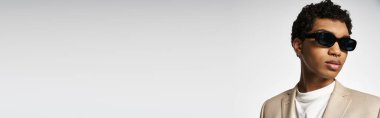 Bronz takım elbiseli ve güneş gözlüklü yakışıklı Afro-Amerikan adam..