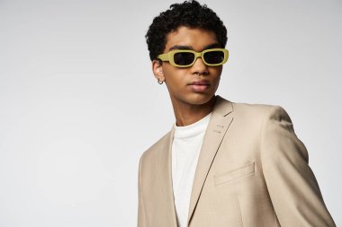 Bronz takım elbiseli ve sarı gözlüklü yakışıklı Afro-Amerikan adam..