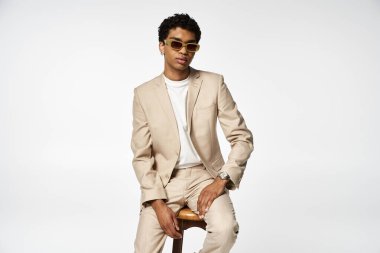 Handsome African American man in stylish sunglasses, sitting on stool. clipart
