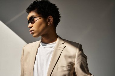 Yakışıklı, kahverengi takım elbiseli, beyaz gömlekli, şık güneş gözlüğü takan Afro-Amerikan bir adam..