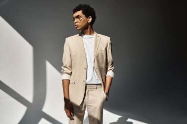 Beyaz bir duvarın önünde duran şık güneş gözlüklü yakışıklı Afro-Amerikan adam..