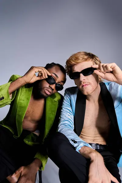 stock image Two handsome, multicultural men in dapper attire sit closely side by side.