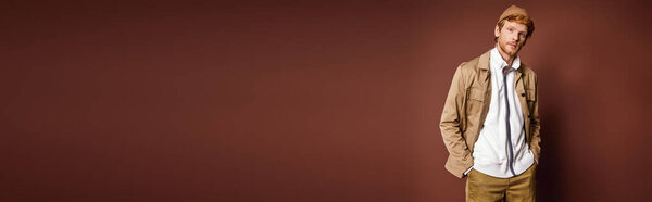 A stylish man standing confidently in front of a vibrant red wall.