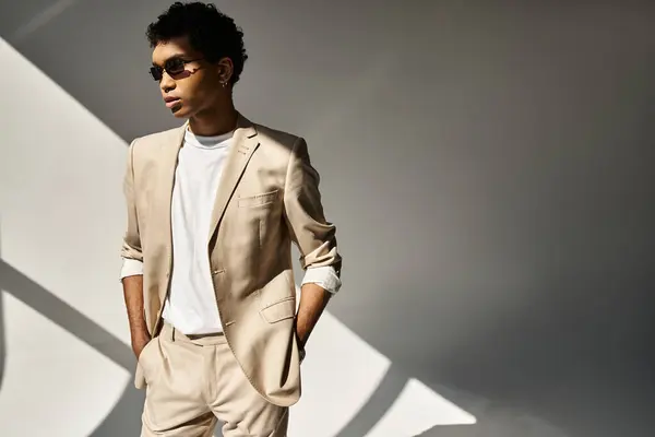 stock image Handsome African American man in tan suit and sunglasses strikes a confident pose.