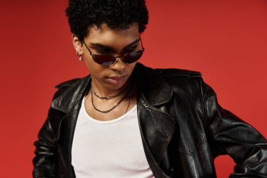 Siyah deri ceketli ve güneş gözlüklü beyaz tişörtlü yakışıklı bir adam..