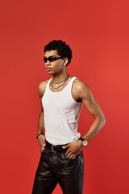 Beyaz atlet ve deri pantolon giymiş şık güneş gözlüklü yakışıklı Afro-Amerikan adam..