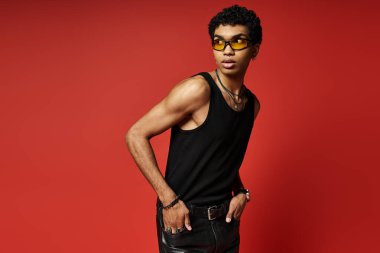 Yakışıklı Afro-Amerikan adam şık güneş gözlüğü, siyah atlet ve deri pantolon giymiş..