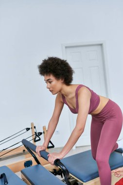 Bir kadın meşgul bir spor salonunda kürek çekme makinesine odaklanır..