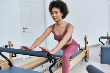 Pembe bluzlu ve taytlı kadın zarif bir şekilde egzersiz yapıyor..