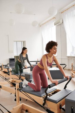 Spor salonundaki genç kadınlar, sabit makinede egzersiz yapıyorlar, kararlı bir şekilde..