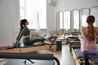 Bir pilates oturumu sırasında denge ve güç sergileyen çeşitli kadın grupları.