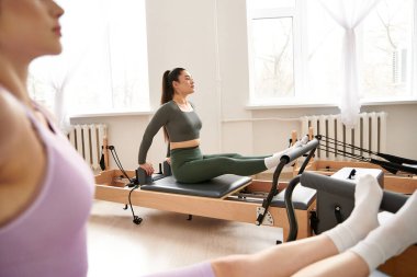 A woman elegantly performing exercises with focus and precision, next to her friend. clipart