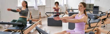 Spor salonundaki bir grup kadın çeşitli egzersizleri aktif olarak yapıyorlar..