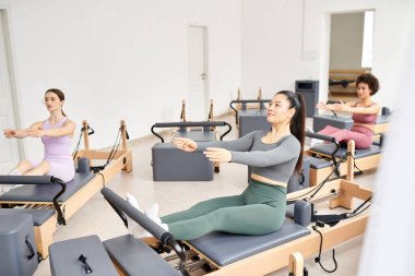 Sınıfta çeşitli kadın grupları pilates egzersizleri yapıyor..