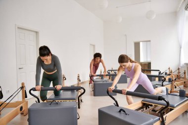 Dinamik bir pilates seansı sırasında birlikte çalışan bir grup şık sporcu kadın..