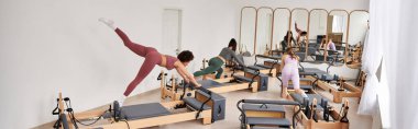 Alluring women engage in a Pilates session in a gym. clipart