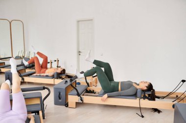 Attractive women engaging in a pilates workout at the gym. clipart