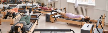 Çeşitli spor ekipmanları üzerine bir pilates dersi veren bir grup güzel kadın..