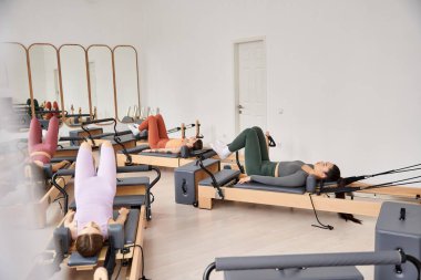 Bir grup sportif kadın bir pilates dersi sırasında senkronize egzersizler yapıyorlar..