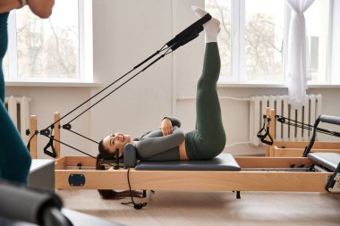 Sportif bir kadın, pilates dersinde dönüş yaparken zarafet ve güç gösterir..