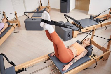 Attractive woman on a pilates lesson, next to friend. clipart