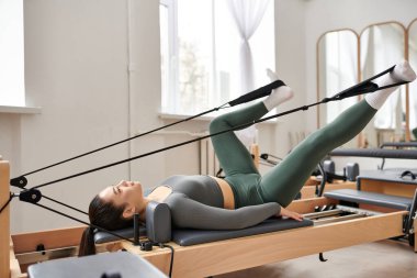 Atletik kadın bir pilates dersi sırasında zarifçe egzersiz yapıyor..