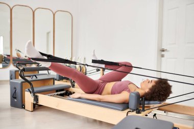 Sportif kadın bir pilates dersi sırasında zarifçe egzersiz yapıyor..