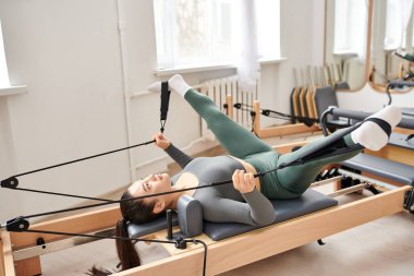Sportif bir kadın pilates dersi sırasında egzersiz yapıyor..