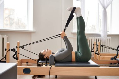 Sportif bir kadın pilates dersinde egzersiz yapıyor..