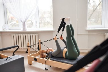 Çekici kadın bir pilates dersi sırasında zarif bir şekilde egzersiz yapıyor..