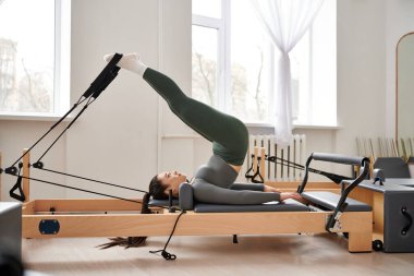 Çekici bir kadın, pilates dersinde zarifçe egzersiz yapar..