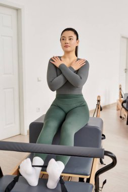 Asyalı sporcu kadın odaklanarak ve kararlılıkla pilates yapıyor..