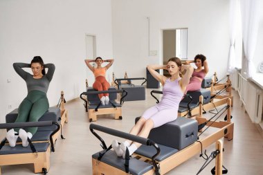 Bir grup sportif kadın bir odada pilates yapıyor..