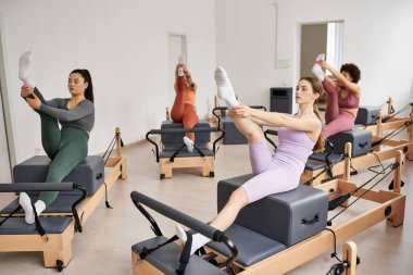 Atletik kadınlar spor salonunda pilates yaparken zarifçe egzersiz yapıyorlar..