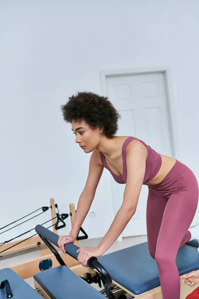 A woman focuses on her rowing machine workout in a busy gym.