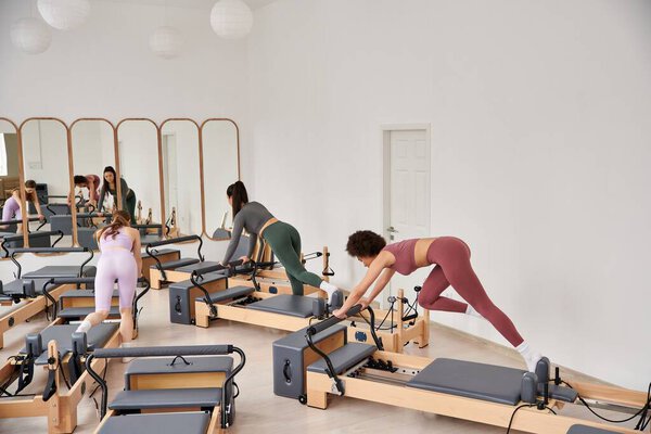 A group of sporty women engaging in a pilates workout at the gym.