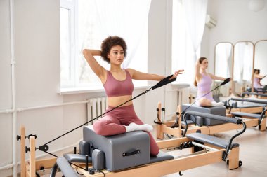 Atletik kadınlar pilates kursuna katılır, esneklik ve çekirdek kuvvete odaklanırlar..
