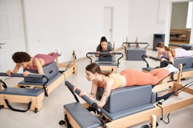 Parlak bir odada pilates yapan sportif kadınlar..