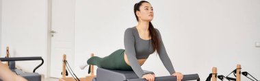Güzel bir kadın pilates dersi sırasında egzersiz yapıyor..