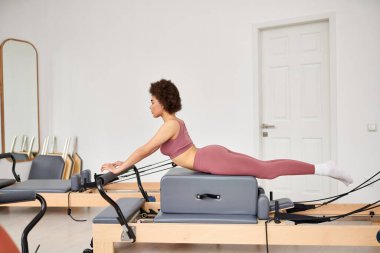 Alluring woman exercising during a pilates lesson. clipart