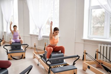 Pilates dersi sırasında dinamik egzersizler yapan sportif kadınlar..